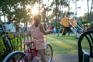 Fillette en vélo devant l'aire de jeux du camping 5 étoiles Lou Pignada à Messanges dans les Landes